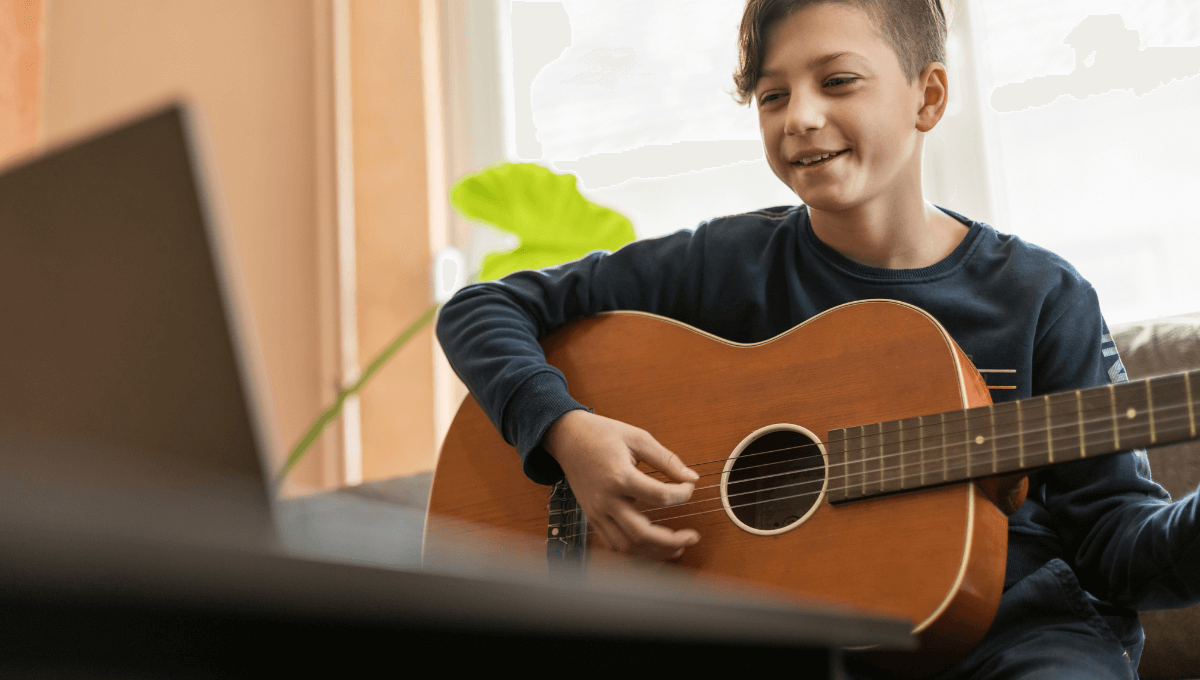 Un enfant suit un cours de guitare en ligne avec WIMA